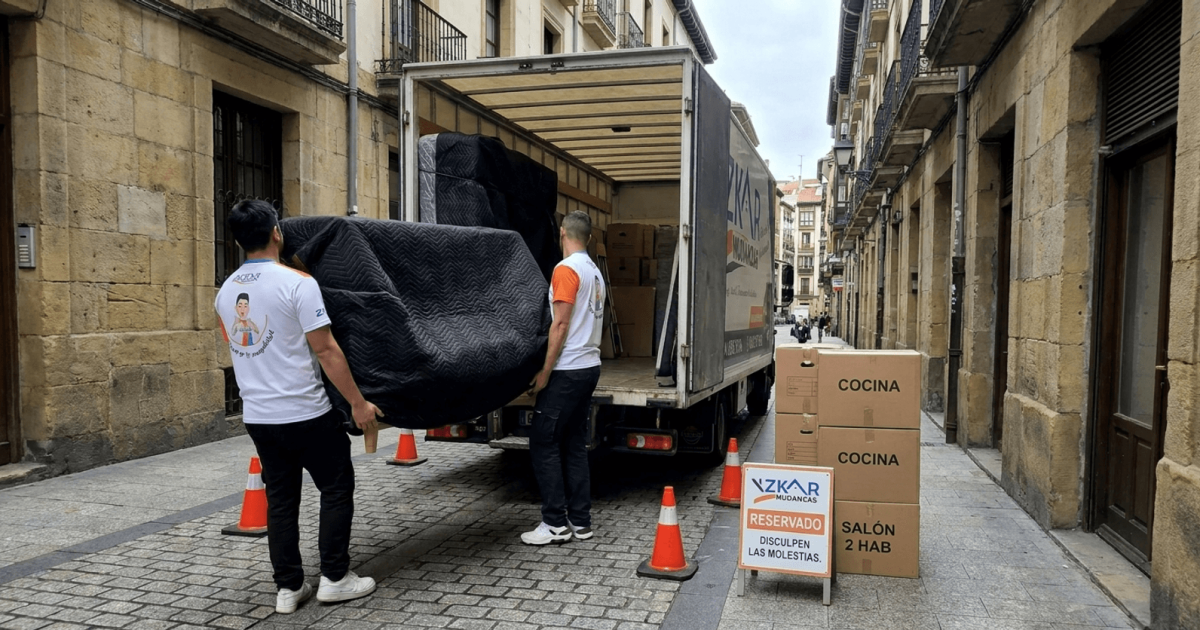 precio mudanza 2 habitaciones Bilbao: operarios de Azkar Mudanzas cargando muebles envueltos en mantas negras junto a su camion en Bilbao
