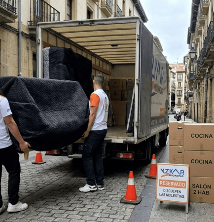 precio mudanza 2 habitaciones Bilbao: operarios de Azkar Mudanzas cargando muebles envueltos en mantas negras junto a su camion en Bilbao