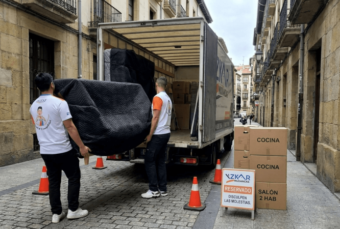 precio mudanza 2 habitaciones Bilbao: operarios de Azkar Mudanzas cargando muebles envueltos en mantas negras junto a su camion en Bilbao