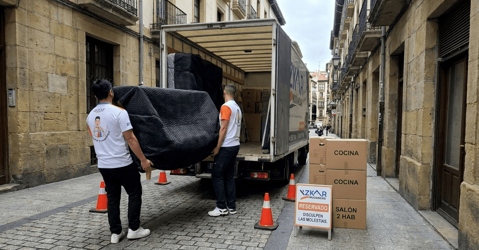 precio mudanza 2 habitaciones Bilbao: operarios de Azkar Mudanzas cargando muebles envueltos en mantas negras junto a su camion en Bilbao